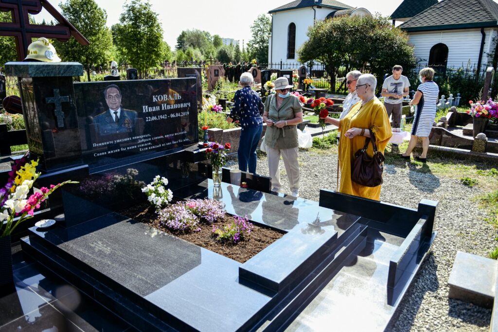 Visitors at a cemetery memorial site, paying respects to the deceased.